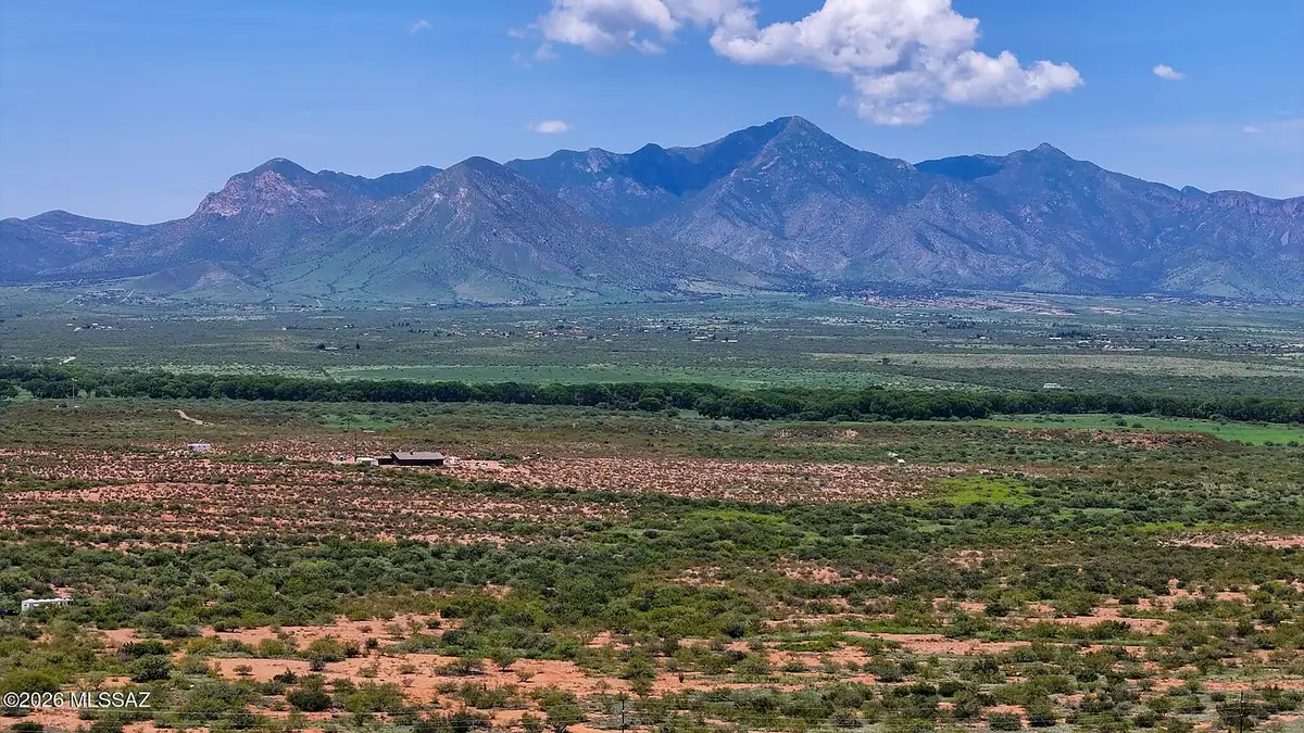 Wide view across the Hereford parcels: green desert scrub in the foreground and the Huachuca Mountains across the San Pedro Valley