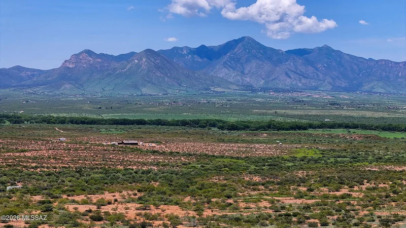 Wide view across the Hereford parcels: green desert scrub in the foreground and the Huachuca Mountains across the San Pedro Valley