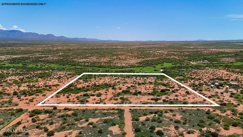 Aerial view of a lot outlined in white with a dirt road along its edge, approximate boundaries only, valley and mountains beyond