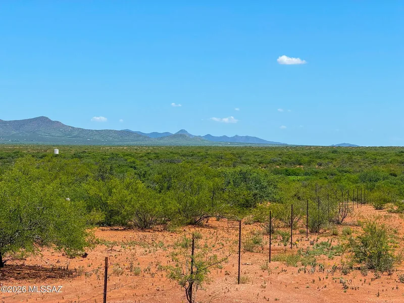 Looking across the parcel fence line and mesquite scrub toward the mountains under a blue sky