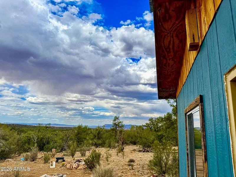 Corner of the teal cabin with its window looking out over the juniper flats and distant valley