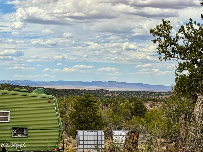 Side of the trailer with white water storage totes beside the cabin, looking out over the valley