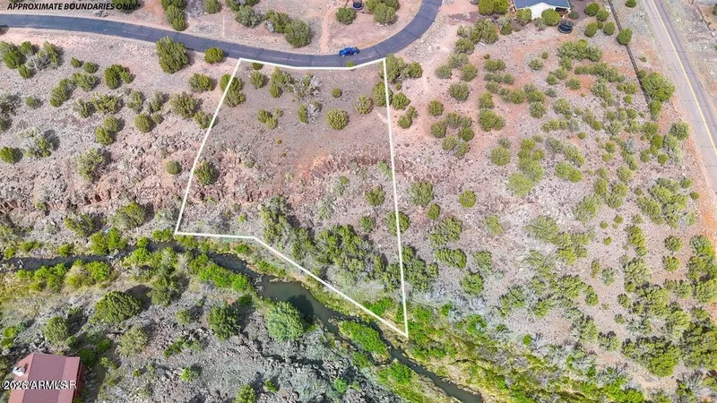 Aerial view of the lot outlined in white at a bend in Creekside Circle, approximate boundaries only, with the creek beside it